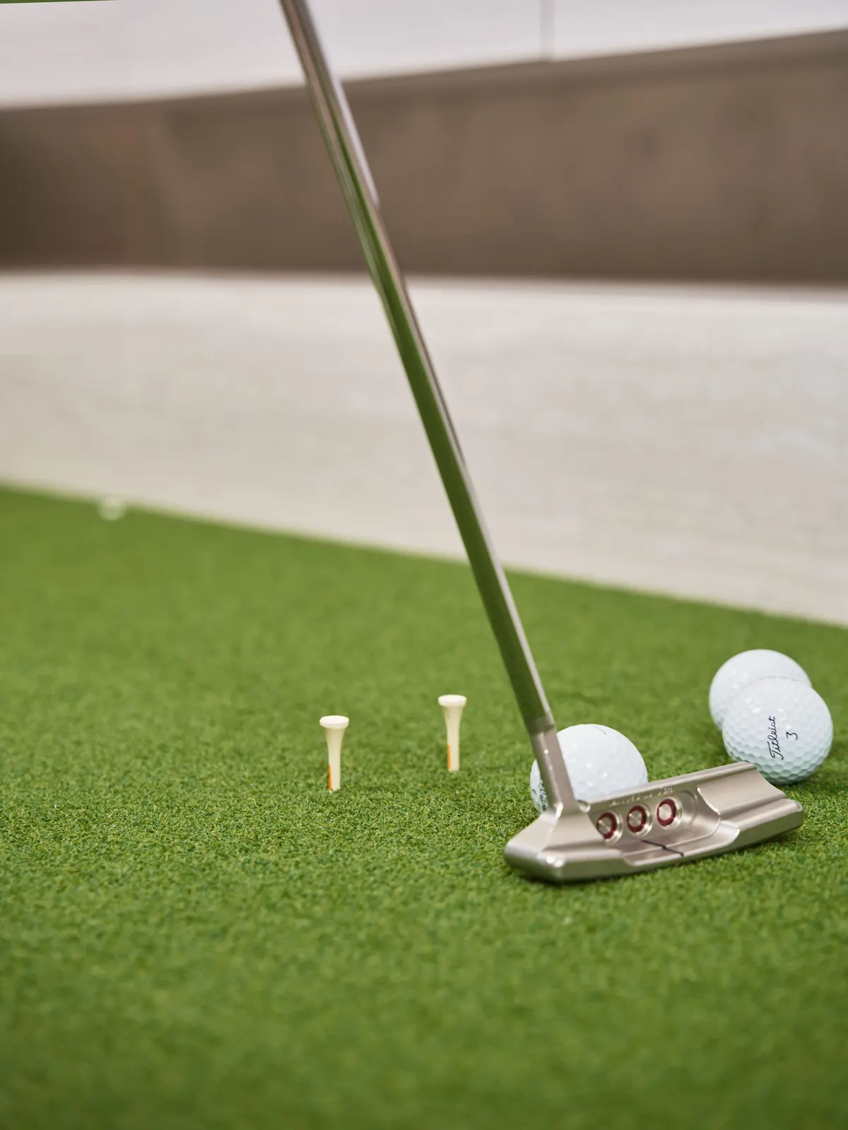 Putter, golf balls, and tees on putting green turf