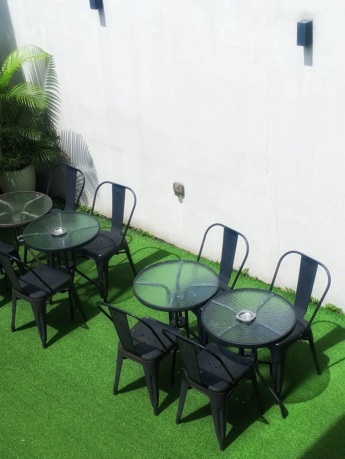 Black cafe tables and chairs on an artificial turf patio